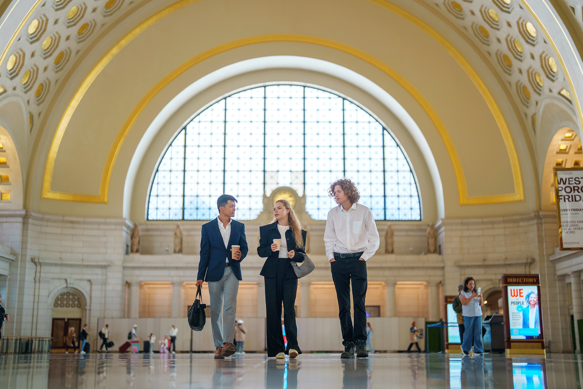 Three people walking in ornate building